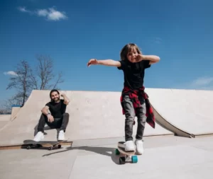 мальчик учится скейт катанию с помощью папы