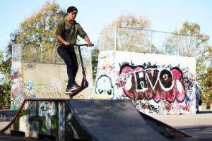 самокатер в парке едет Skate Scool занимается на тренировке на фанбоксе из фанеры