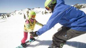сноуборд инструктор за руки держит ученицу на склоне аккуратно